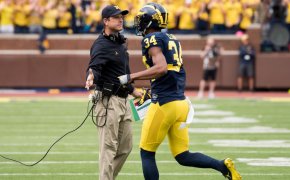 Jim Harbaugh high fiving one of his Michigan players.