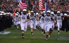 Navy football team running onto the field