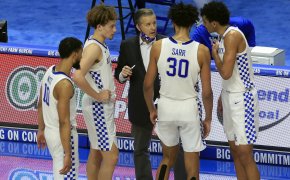 Kentucky's men's basketball head coach John Calipari talking to his players on the court during a stoppage of play during a game.
