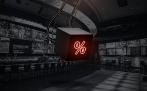 image of a hanging screen with a percentage sign displayed on it in front of a sports book background