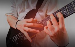 close up image of hands playing an electric guitar