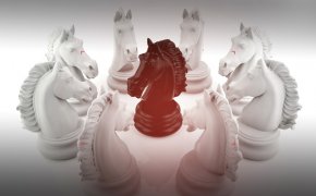 image of white chess pieces surrounding a single black chess piece