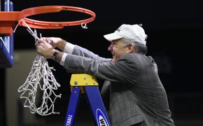 Hofstra head coach Joe Mihalich cutting the netting of the basket off after winning the championship.
