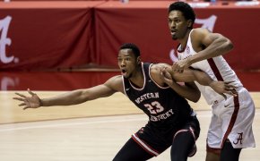 Western Kentucky center Charles Bassey and Alabama guard battling under the net during a basketball game.