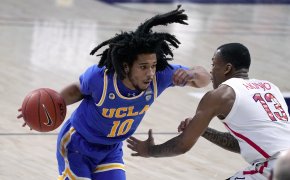 UCLA guard Tyger Campbell driving on Arizona guard James Akinjo during a game.