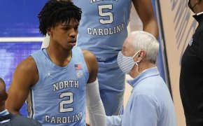 North Carolina head coach Roy Williams talking to her player Caleb Love as he's coming off the court.