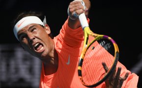 Rafael Nadal following through on a serve during a tennis match.