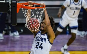 Villanova forward Jeremiah Robinson-Earl hanging from the basket after a dunk during a NCAA men's basketball game.