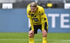 Dortmund's Erling Haaland looking disappointed with his hands on his knees during a soccer match.