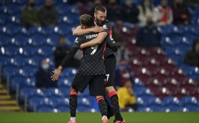Liverpool's Nathaniel Phillips and Roberto Firmino celebrating and hugging each other after scoring a goal during a soccer match.