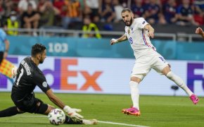 France's Karim Benzema kicking the ball past Portugal's goalkeeper to score during a soccer match.