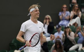 Denis Shapovalov celebrating with a first pump and smile after winning a match at Wimbledon.