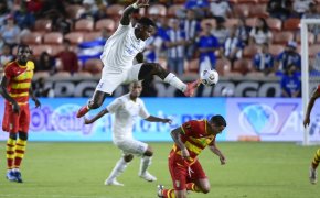 Honduras player leaping in air to control soccer ball with left foot in front of defender