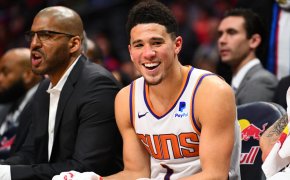 Phoenix Suns guard Devin Booker sitting on the bench smiling.
