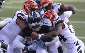 Tennessee Titans' Derrick Henry being tackled by Cincinnati Bengals' players.