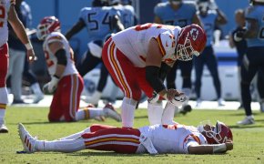 Patrick Mahomes laying on back, teammate trying to help him up