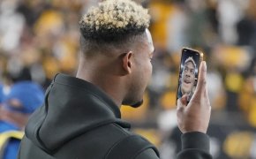 Pittsburgh Steelers wide receiver JuJu Smith-Schuster facetiming on his phone on the field.