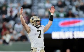 New Orleans Saints quarterback Taysom Hill reacting with his hands in the air on the field during a game.