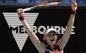 Paula Bados celebrating with her hands up in the air after defeating an opponent during a tennis match.