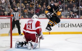 Sidney Crosby leaping to avoid a shot during an NHL game.