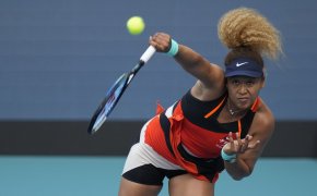 Naomi Osaka hitting a serve during a match at the 2022 Miami Open.