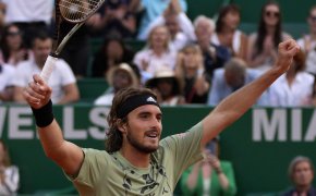 Stefanos Tsitsipas celebrating with his hands up in the air after a win.