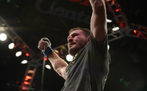 Stipe Miocic arms up celebrating sitting on UFC Octagon cage