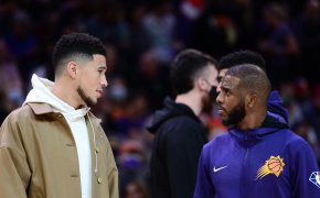 Devin Booker in street clothes talking to Chris Paul