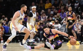Devin Booker slips with Steph Curry looking on