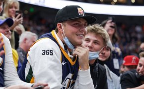 New York Jets quarterback Zach Wilson sits on court side watching the game between the Utah Jazz and the Golden State Warriors