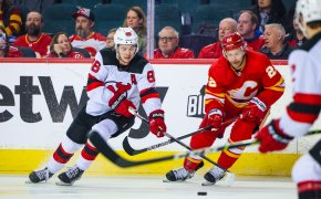 New Jersey Devils center Jack Hughes and Calgary Flames center Trevor Lewis battle for the puck