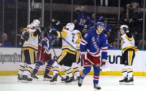 Pittsburgh Penguins center Evgeni Malkin celebrating a triple-OT goal with teammates as New York Rangers players skate off the ice
