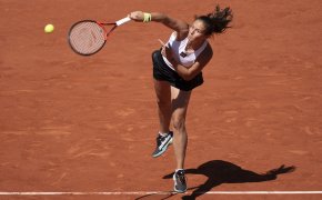 Daria Kasatkina serving a ball during a tennis match.