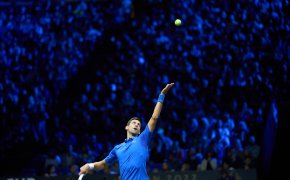 Novak Djokovic hitting a serve during a tennis match.