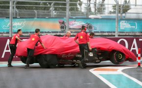 Crew members push the wrecked car of Ferrari driver Charles Leclerc off the track