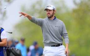 Patrick Cantlay throws a golf ball to his caddie
