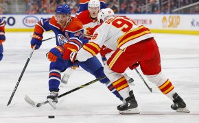 Edmonton Oilers forward Connor McDavid tries to carry the puck around Calgary Flames defensemen Ilya Solovyov