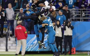 Ravens tight end Isaiah Likely hauling in a pass between two Jaguars defenders.