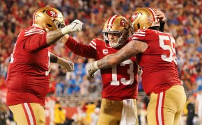 Three players on the San Francisco 49ers celebrating after a successful play.