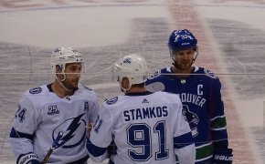 Steven Stamkos at center ice flanked by a teammate and Henrik Sedin