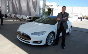 Elon Musk posing with a Tesla car