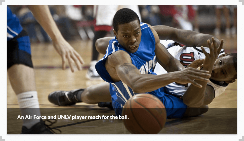 A photo showing an Air Force and UNLV player both reach for a ball during a basketball game