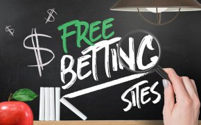 a hand holding a magnifying glass up to a chalkboard that says Free Betting Sites